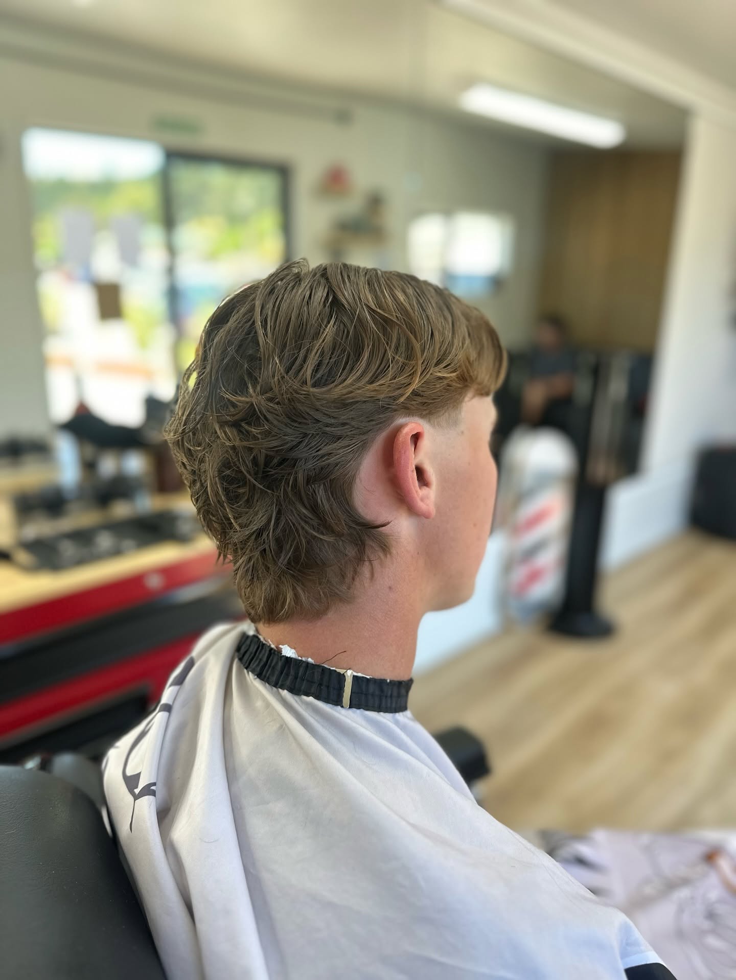 Side view of a finished blond mullet, cut at Highway Barbers.